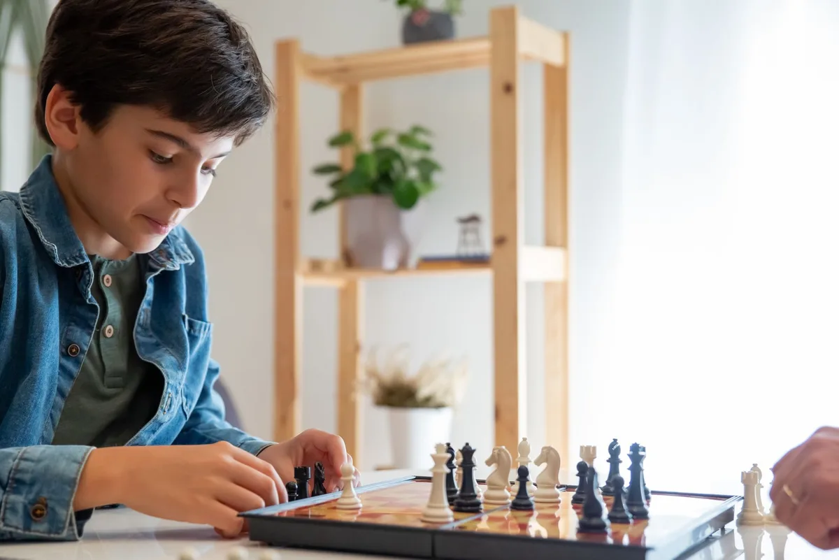 A young boy attentively playing chess at home, showcasing strategic thinking and concentration.