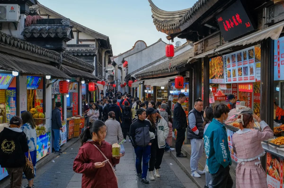 Crowded street market in Asia with traditional architecture and vibrant food stalls.