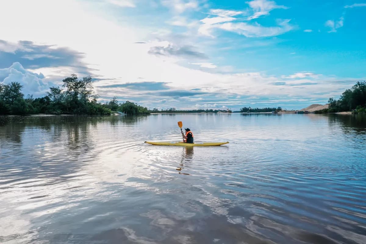 A scenic kayak ride on a tranquil river in Terengganu, Malaysia, surrounded by lush greenery.