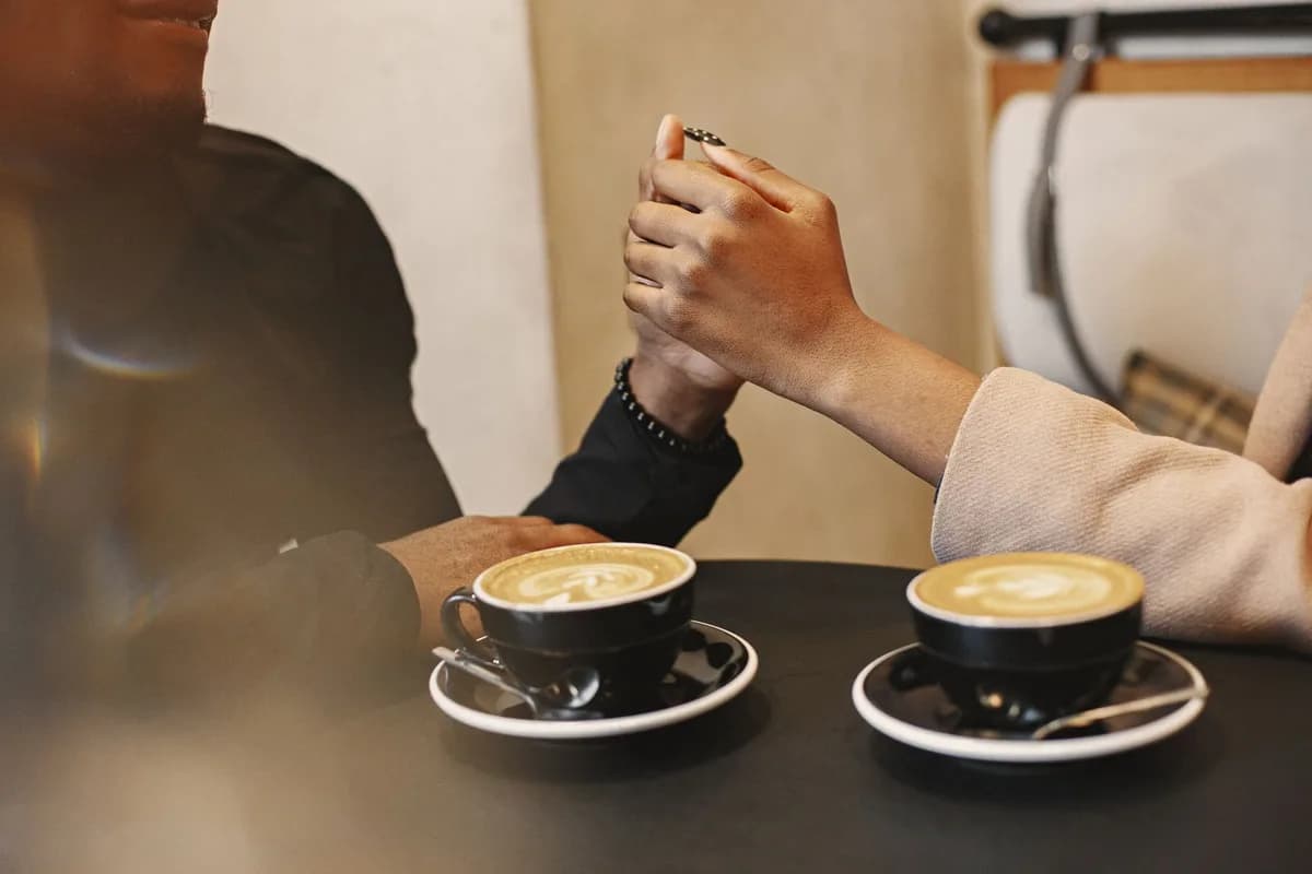 A couple holding hands over coffee in a cozy cafe setting.