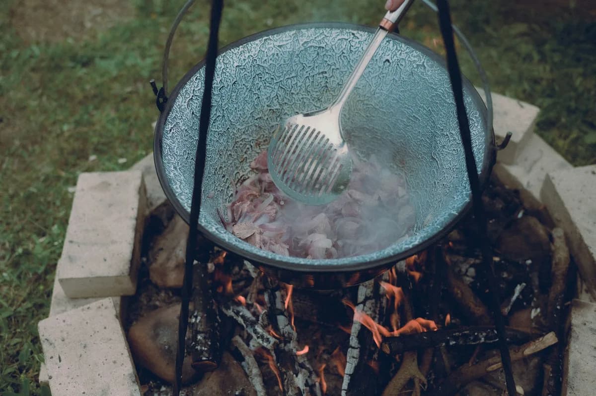A rustic outdoor cooking scene with a pot over a campfire, perfect for travel and adventure themes.