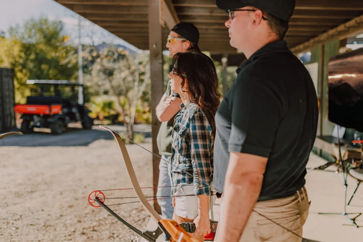 A group of adults practicing archery at an outdoor range, focusing on technique.