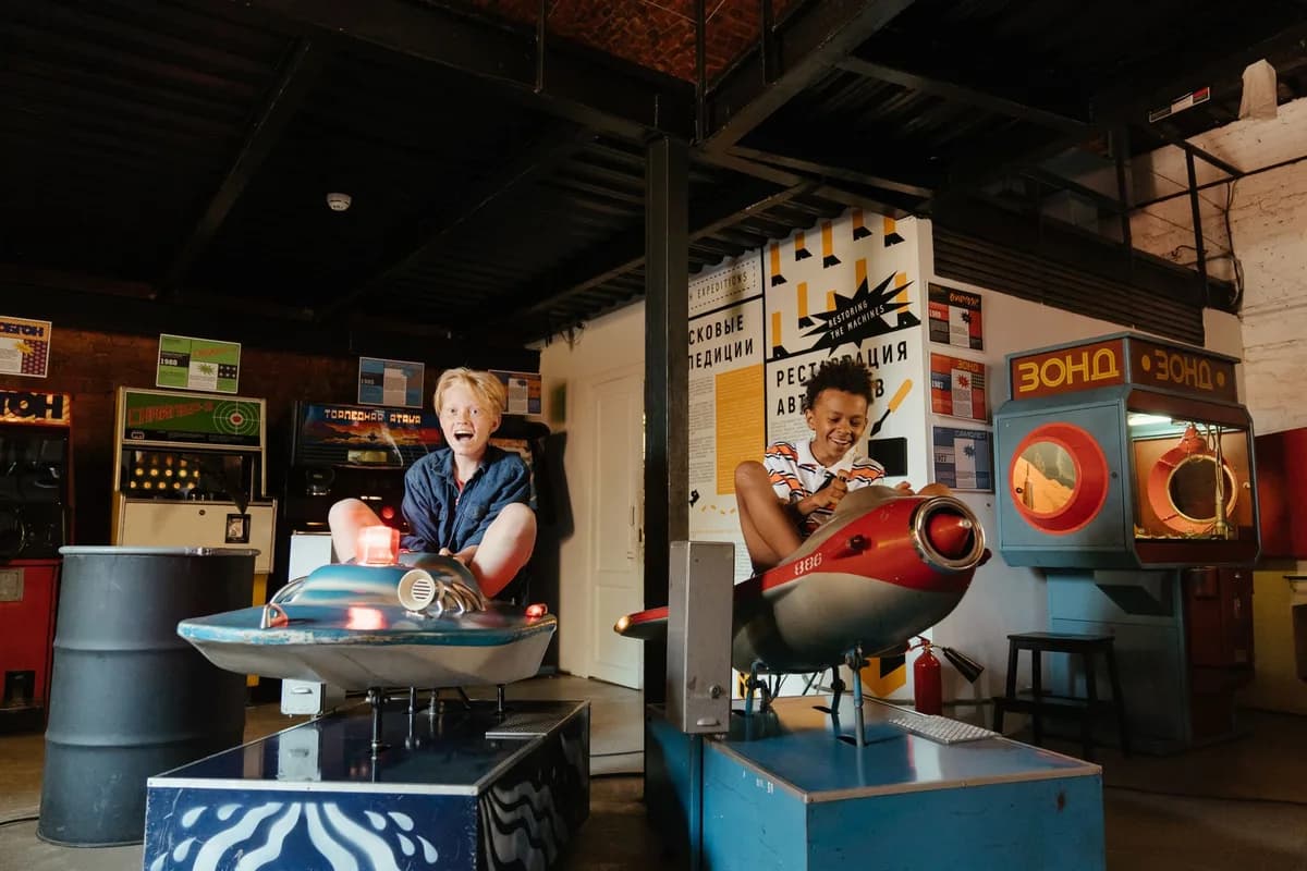 Playful teenagers having fun on vintage arcade amusement rides indoors.
