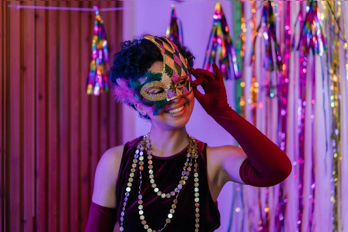 Elegant woman in a mardi gras mask, celebrating at a bright, colorful party.