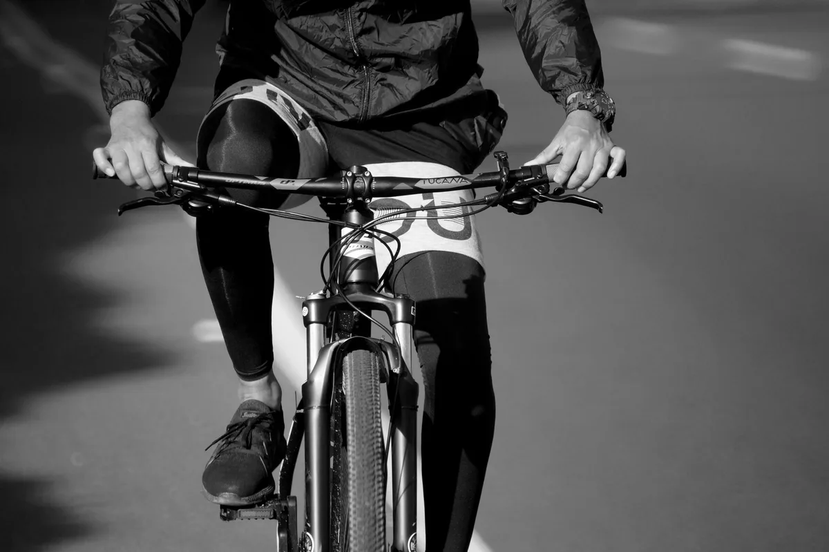 A close-up black and white image of a mountain biker in motion, highlighting the sport's dynamic nature.