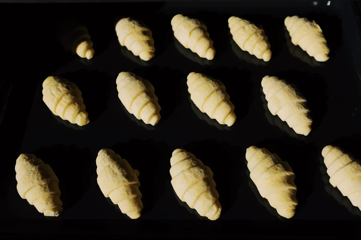 Fresh unbaked croissants aligned on a tray, capturing the essence of baking in progress.