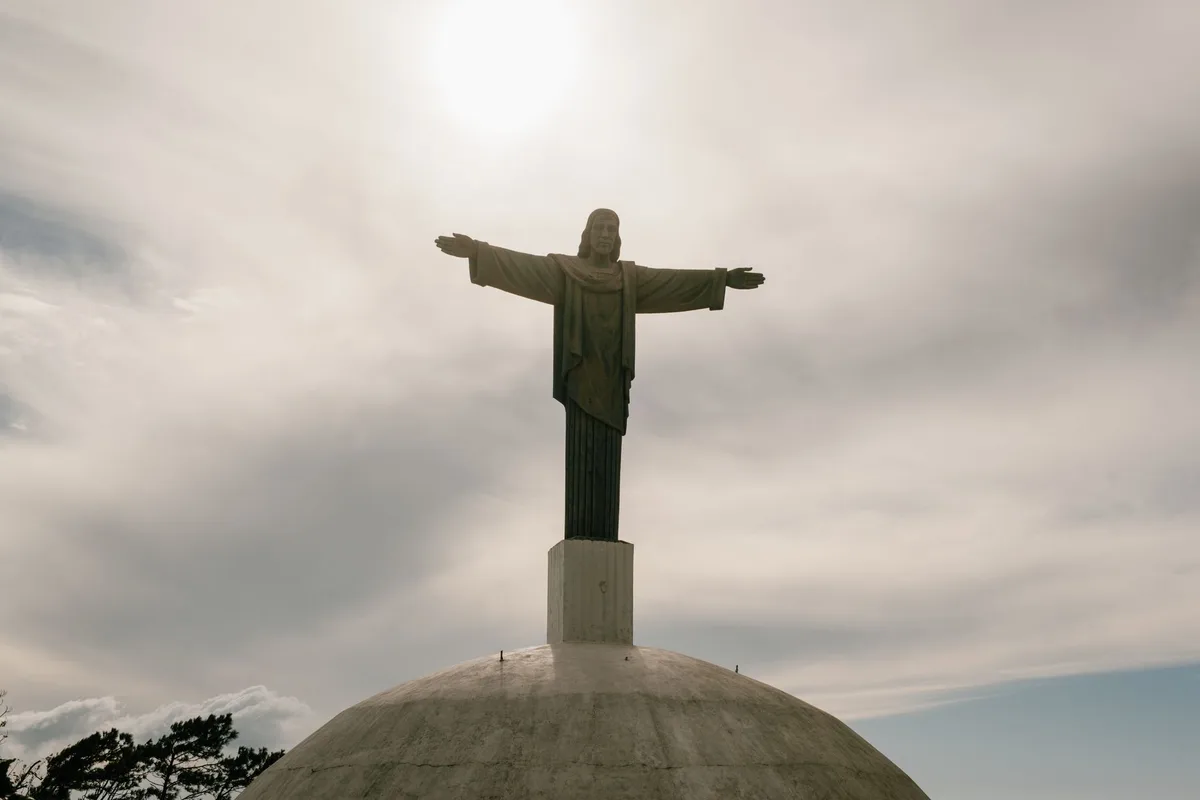 Christ statue stands tall against a dramatic cloudy sky, evoking a sense of peace.