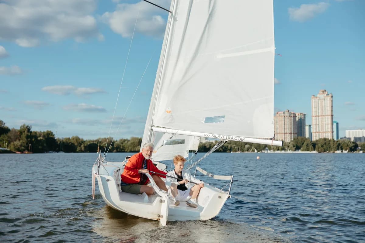 Grandfather and grandson sailing together on a sunny day, bonding and enjoying leisure time on the water.