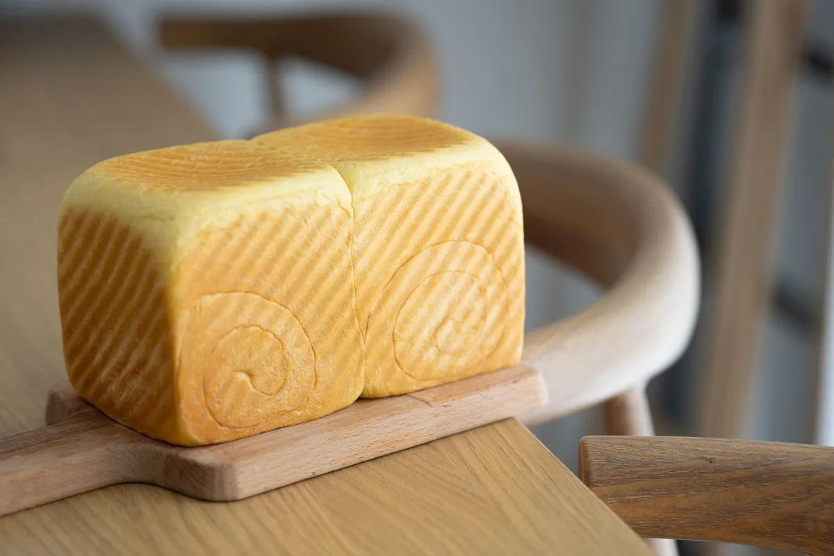 Close-up of a freshly baked artisan bread loaf on a wooden board, showcasing texture and detail.