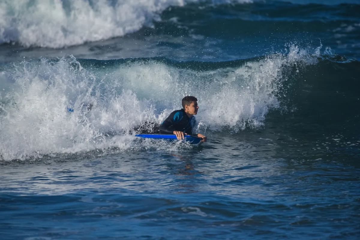 A man enjoying bodyboarding on ocean waves during the daytime, embracing the thrill of surfing.
