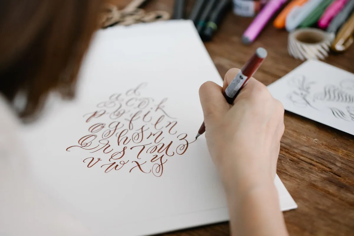 Close-up view of elegant calligraphy lettering in progress on paper.