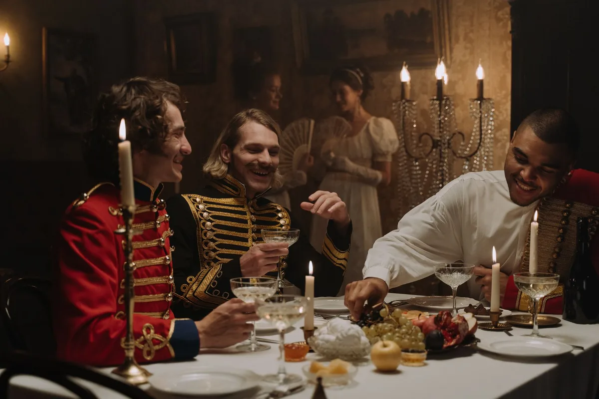 Friends in period costumes sharing a candlelit dinner.