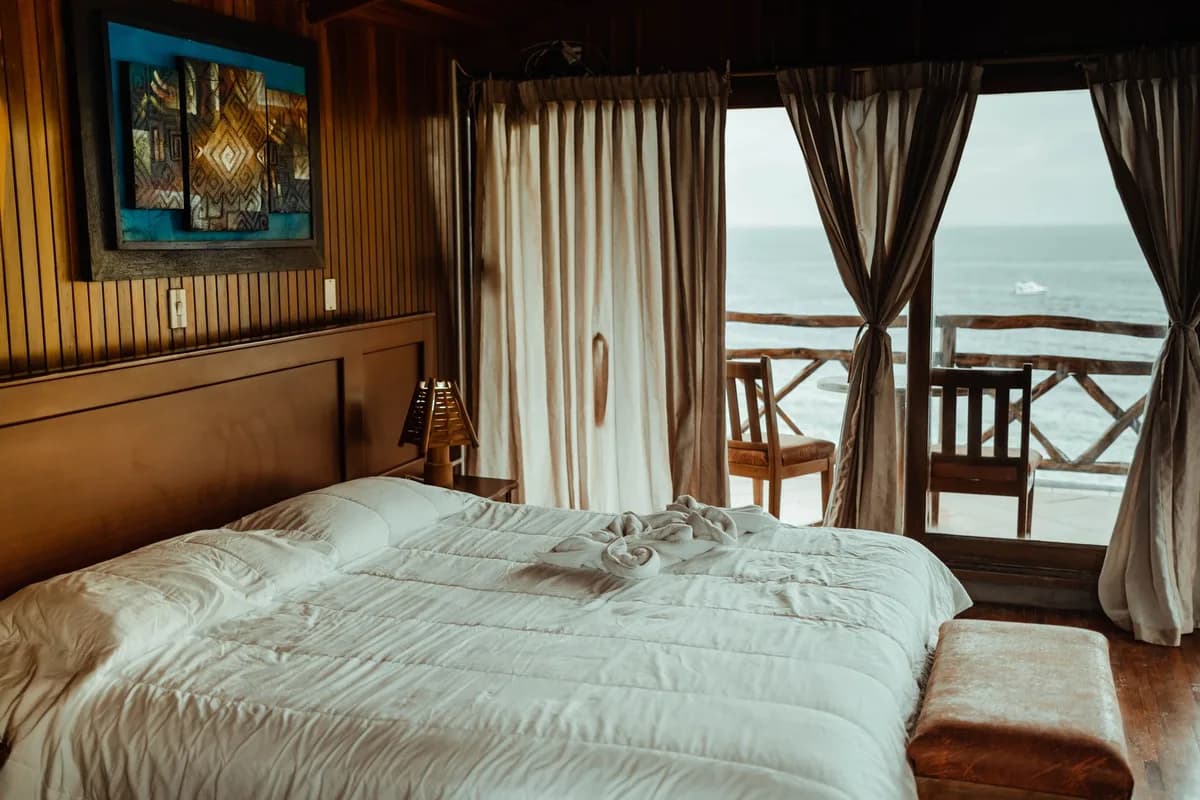 Luxurious seaside bedroom featuring a plush bed, elegant decor, and stunning ocean view for a serene escape.