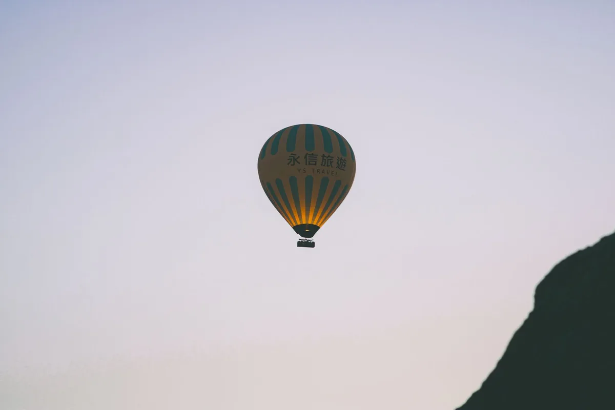 A hot air balloon floating above mountains at twilight.