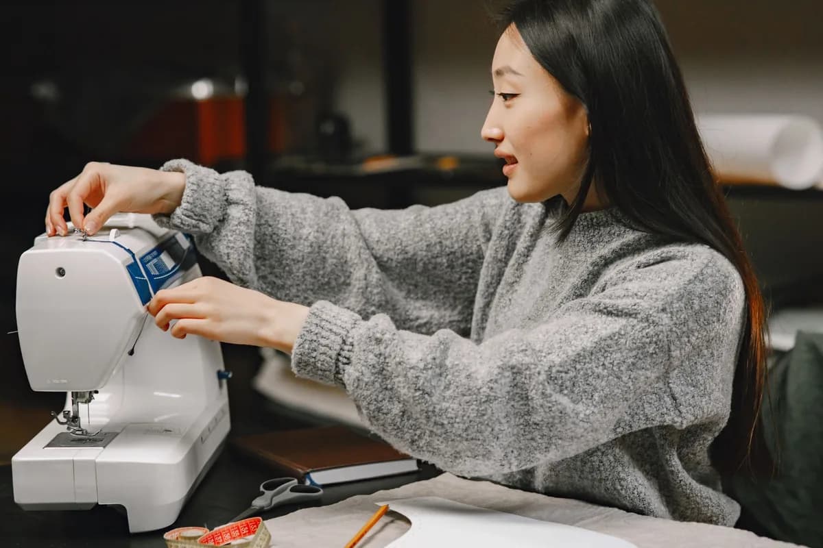 Female sewing enthusiast working at a sewing machine in a cozy home workspace.