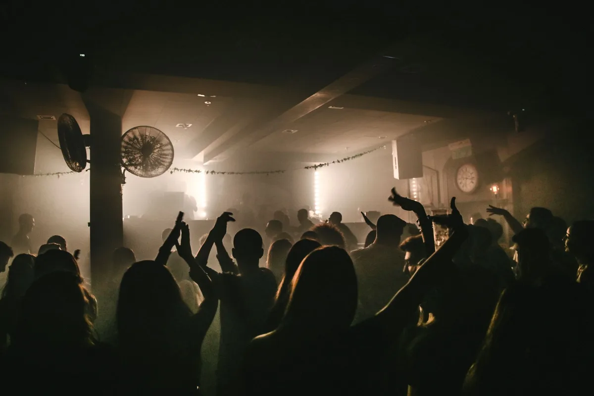 A lively dance floor with people enjoying music in a dimly lit nightclub environment.