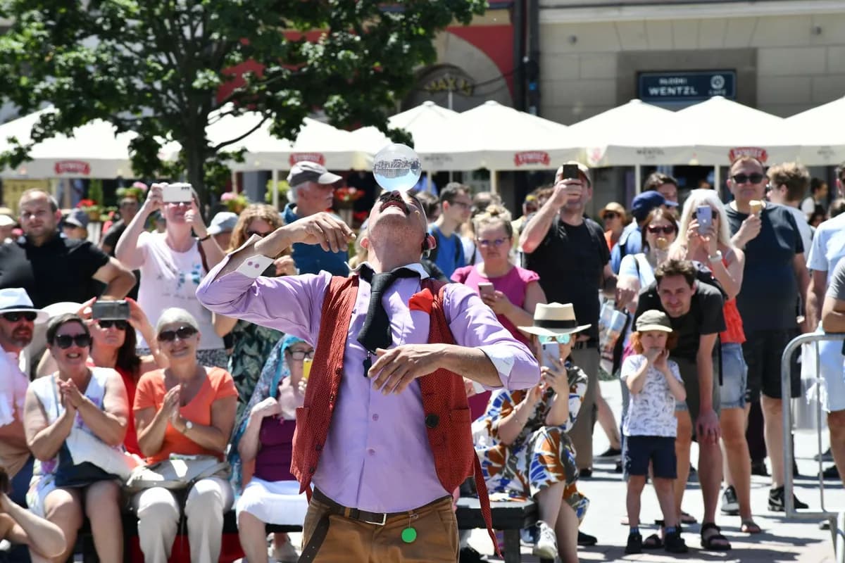 A street performer entertaining a crowd in a lively urban area on a sunny day.