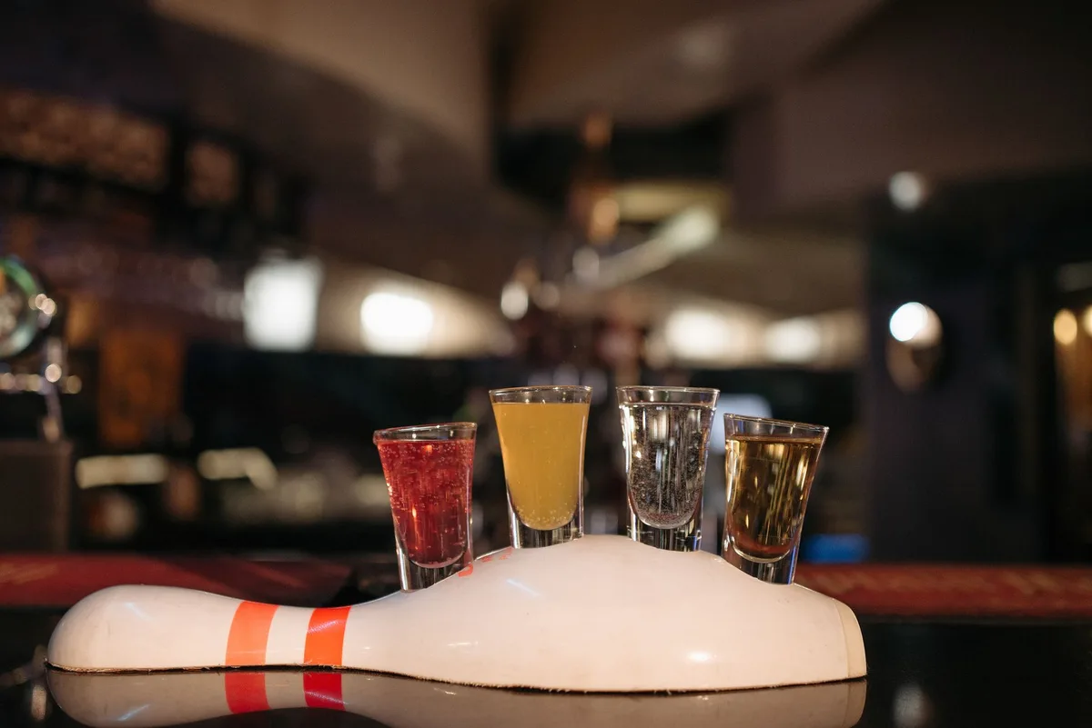 Vibrant shot glasses on a bowling pin stand at a cozy bar.