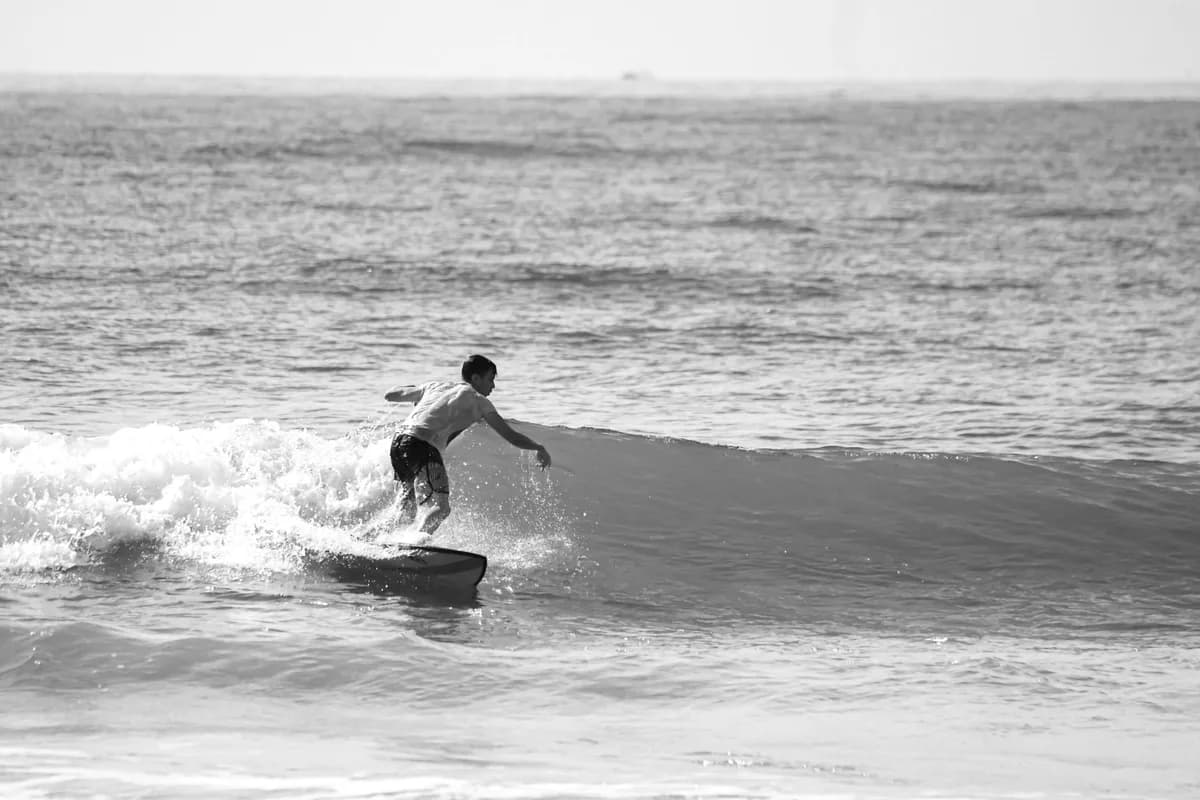 Black and white photo of a surfer skillfully riding a wave in the ocean.