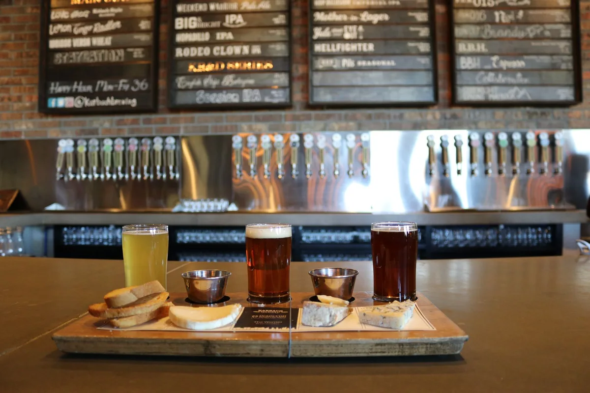 A selection of craft beers served with cheese and bread on a bar counter.