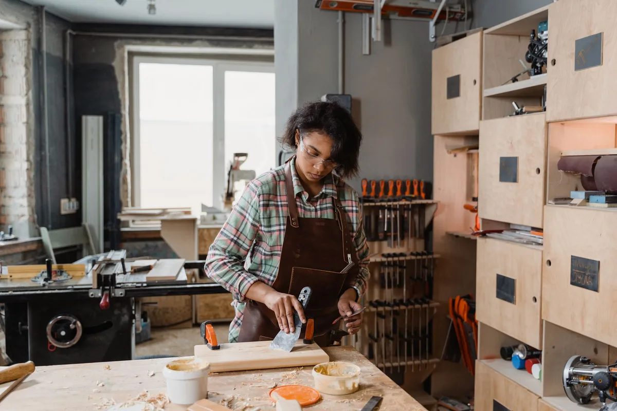 Woman using hand tools in a cozy woodworking studio, crafting wood pieces with skill.