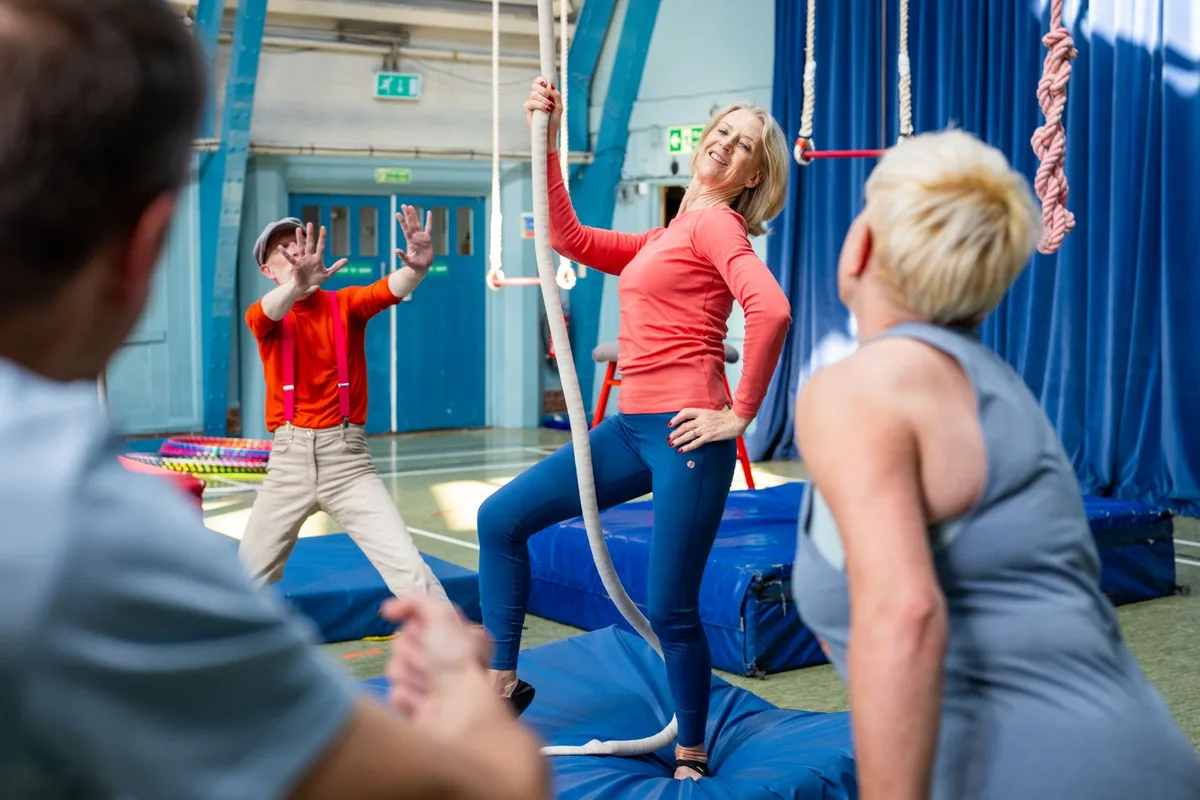 Older adults having fun practicing circus arts inside a gymnasium.