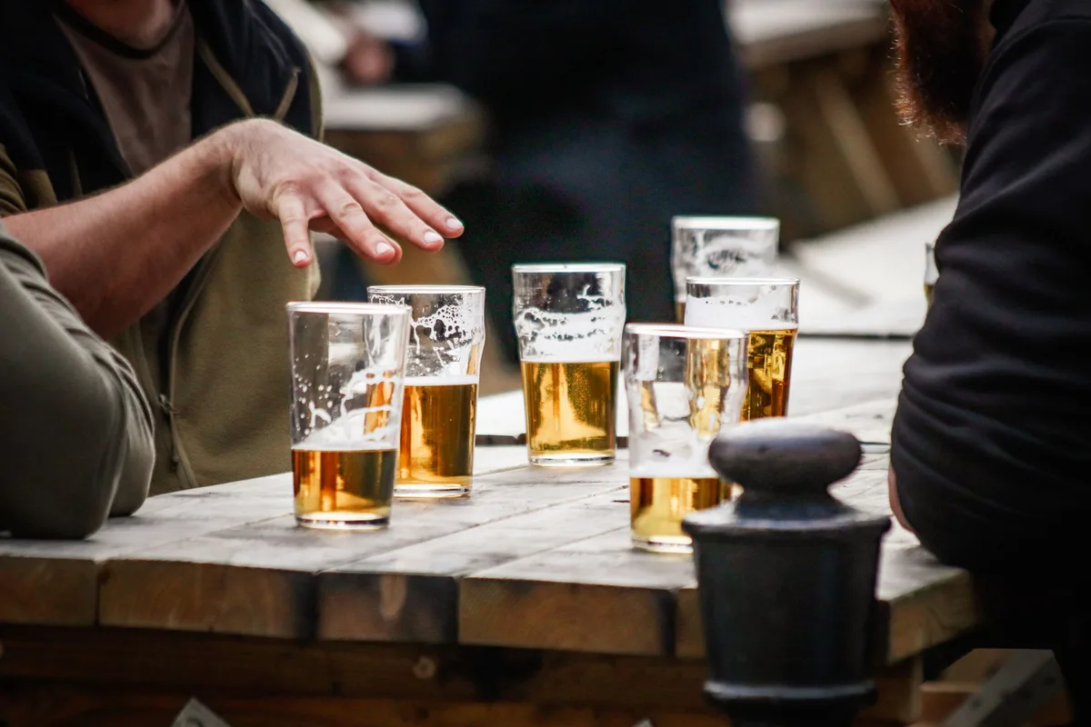Friends enjoy beer at an outdoor table, featuring casual vibes and camaraderie.