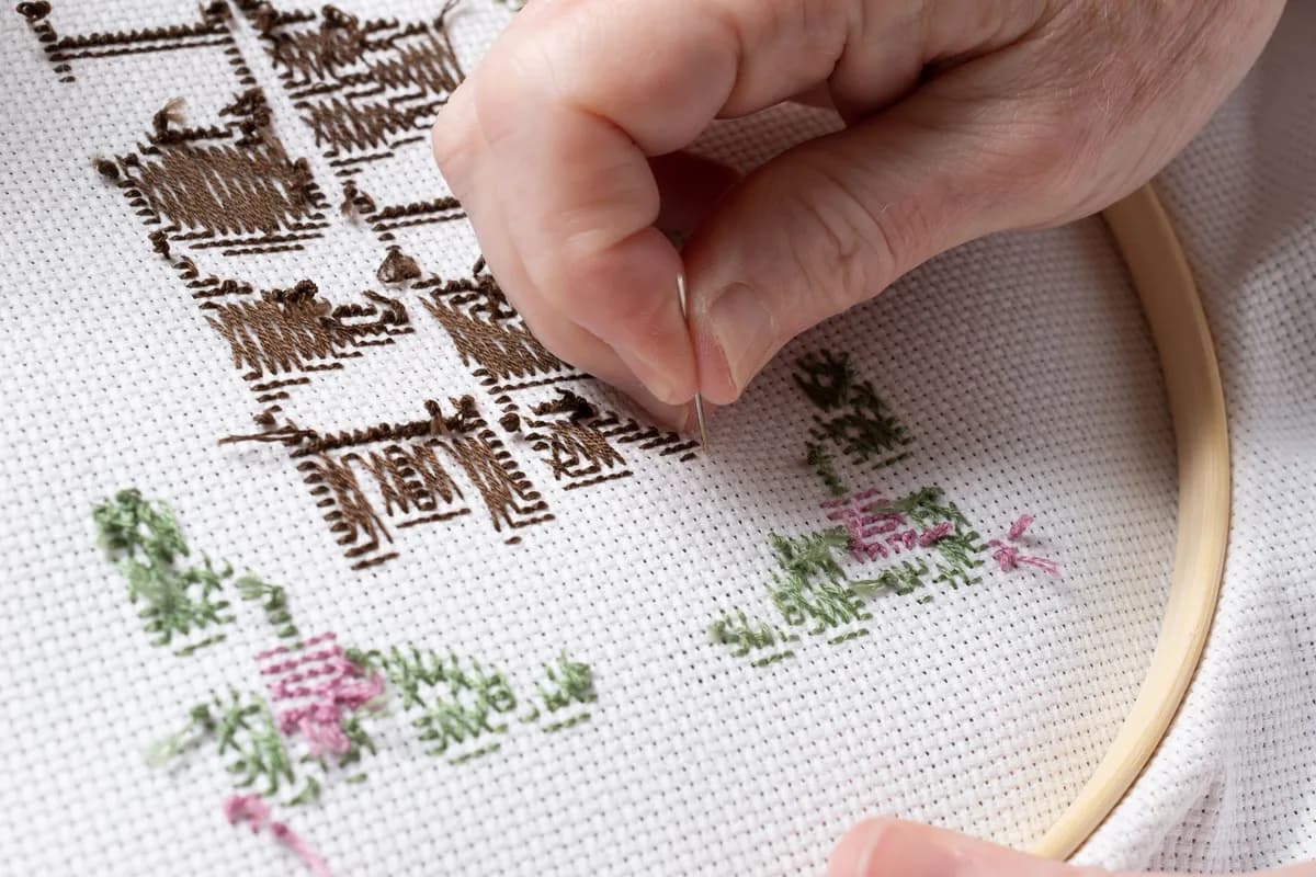 A detailed view of hand embroidering a fabric with traditional patterns.