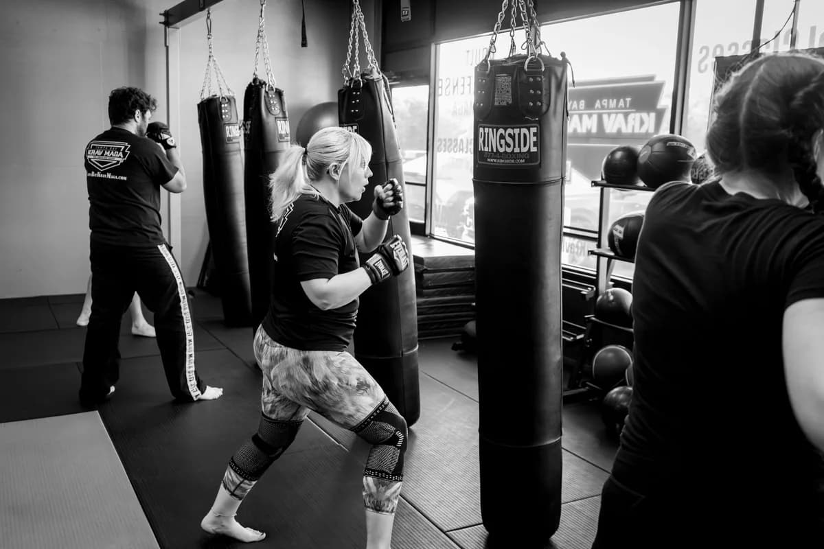 Adults in a martial arts studio practicing with punching bags, focusing on skill and fitness.