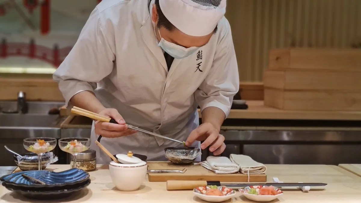 A skilled Japanese chef meticulously prepares sashimi in an intimate restaurant setting.