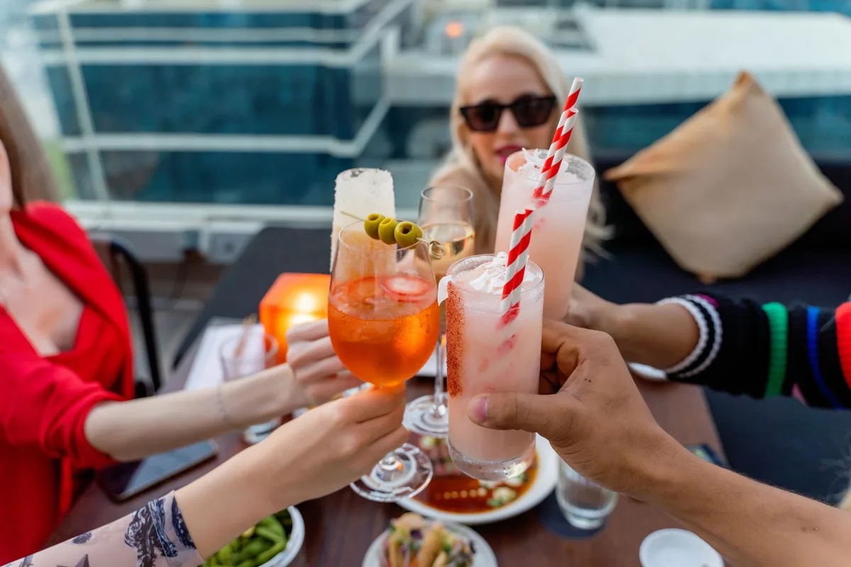Friends raising glasses in celebration at a stylish rooftop bar in Dubai.