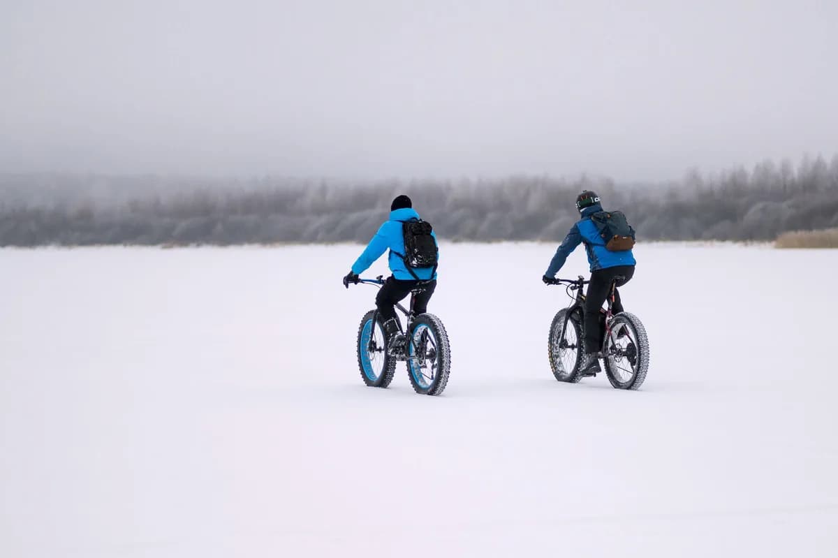 Two cyclists riding fat bikes through a snowy landscape, embracing winter sports and adventure.