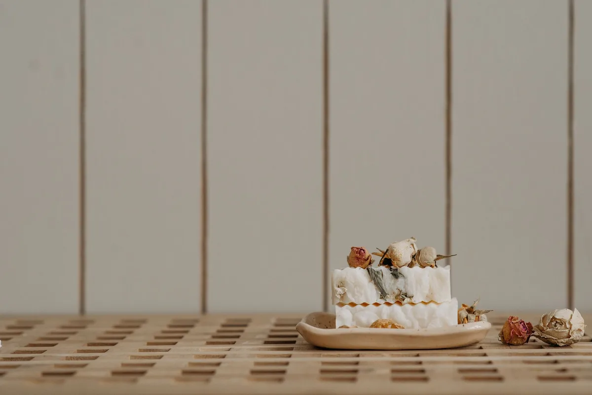 Artisan bar soap with dried roses on a wooden dish, perfect for natural skincare enthusiasts.