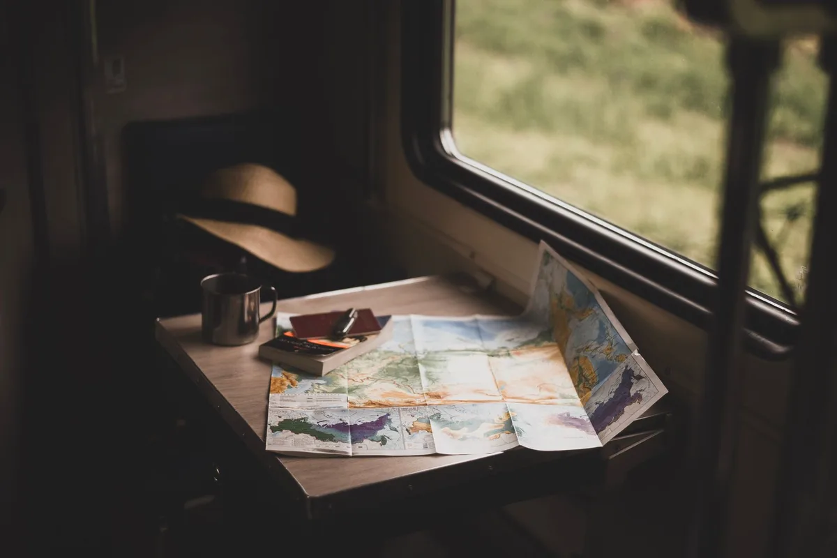 A traveler looking at a map beside a train window.