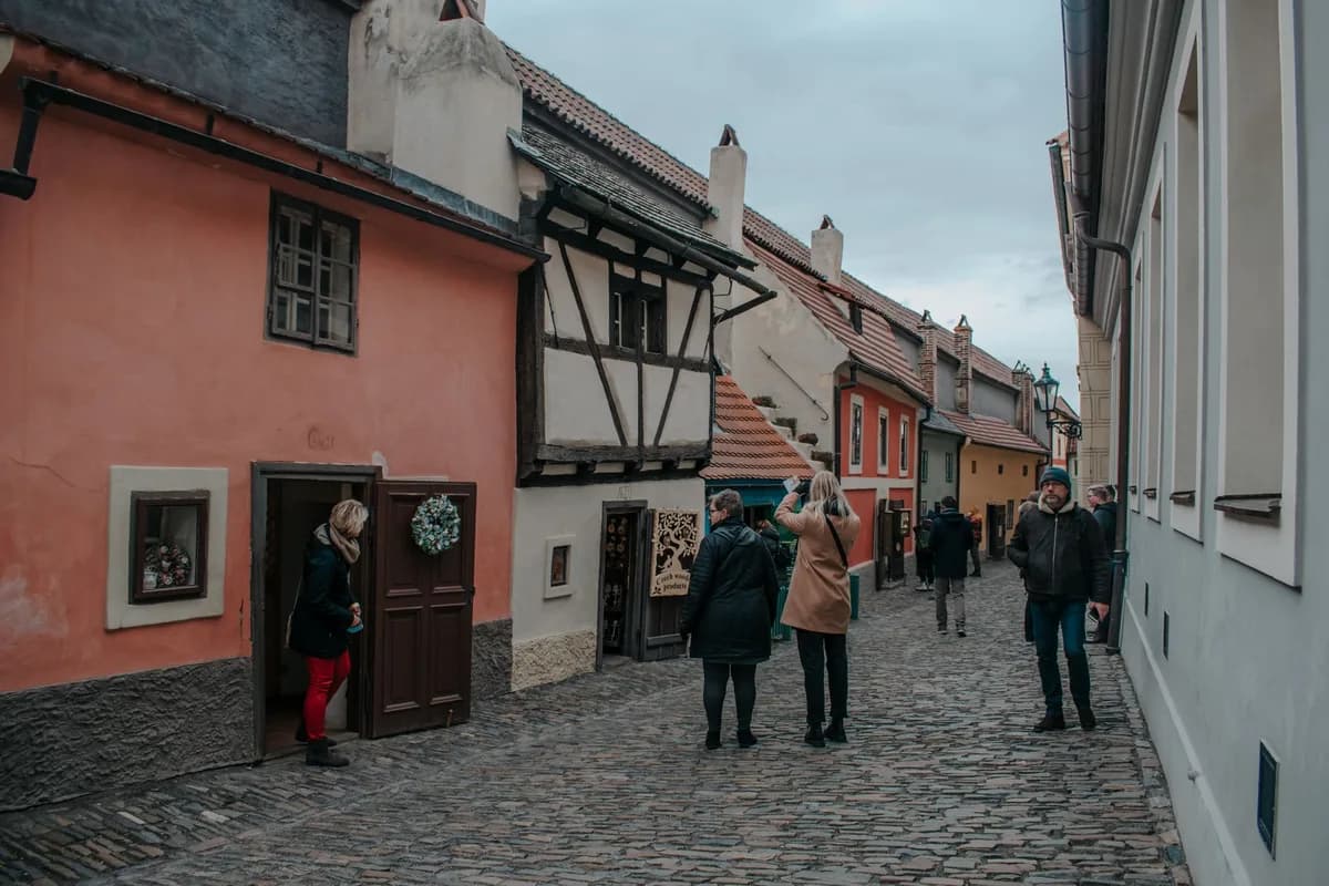 Charming scene on Golden Lane in Prague with people walking by colorful medieval houses.