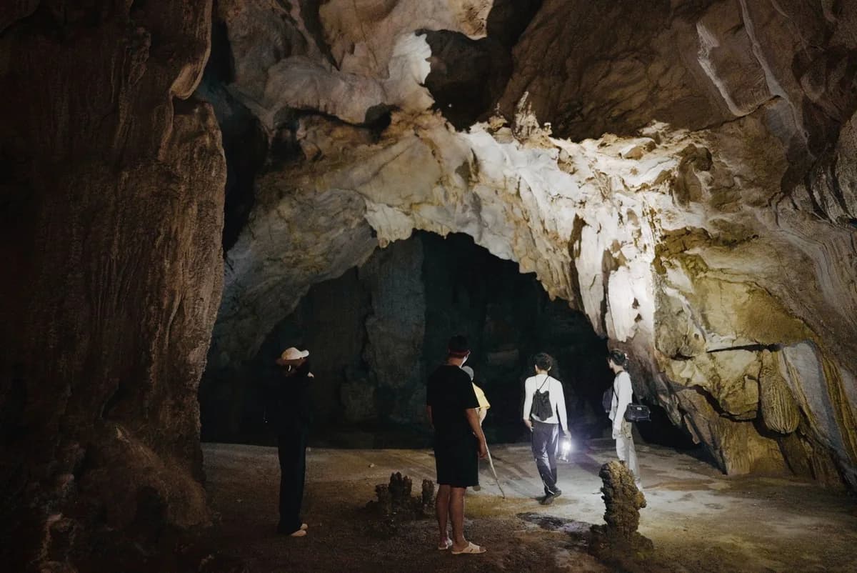 Adventurers explore a vast, dimly lit cave with stunning rock formations.