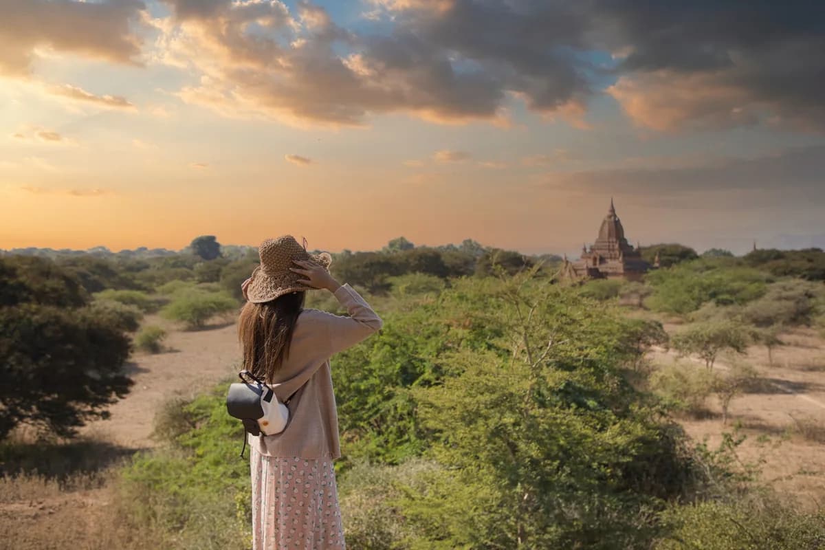 Woman in crochet hat exploring Bagan temple landscape at sunset, Myanmar.