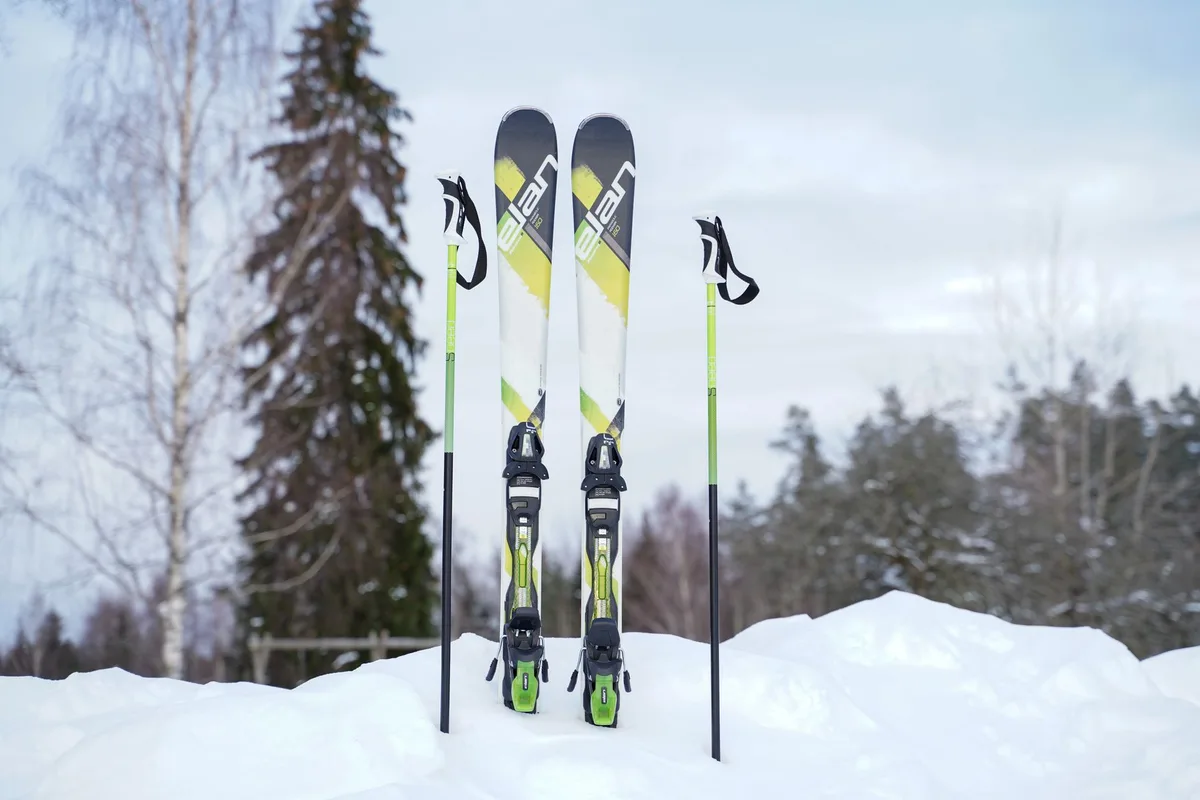 Pair of skis and poles standing upright in a snowy winter outdoor setting.