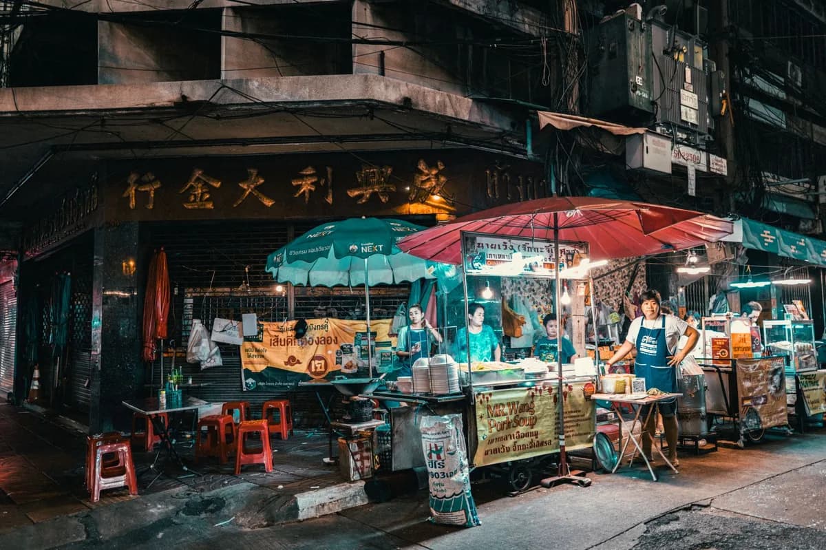 Vibrant night market scene in Bangkok showcasing street food vendors and bustling activity.