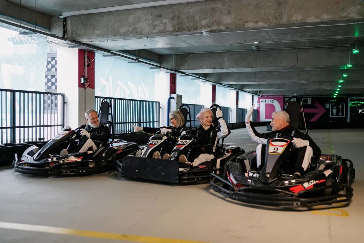 Elderly friends having fun racing go-karts indoors, demonstrating sportsmanship and friendship.