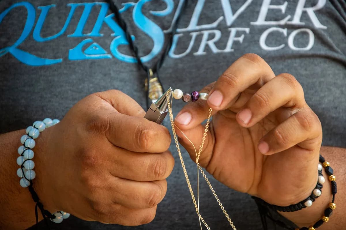 Close-up of hands crafting handmade jewelry with beads and chains, showcasing creativity and artistry.
