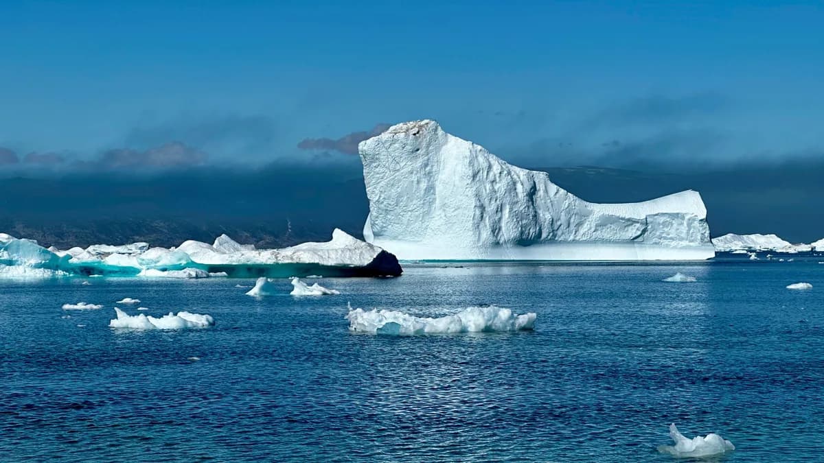 Stunning view of vast iceberg in clear blue waters of Greenland, showcasing nature's serene beauty.