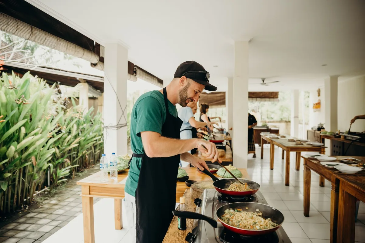 A chef prepares a meal in an open-air kitchen setting in Bali, Indonesia.