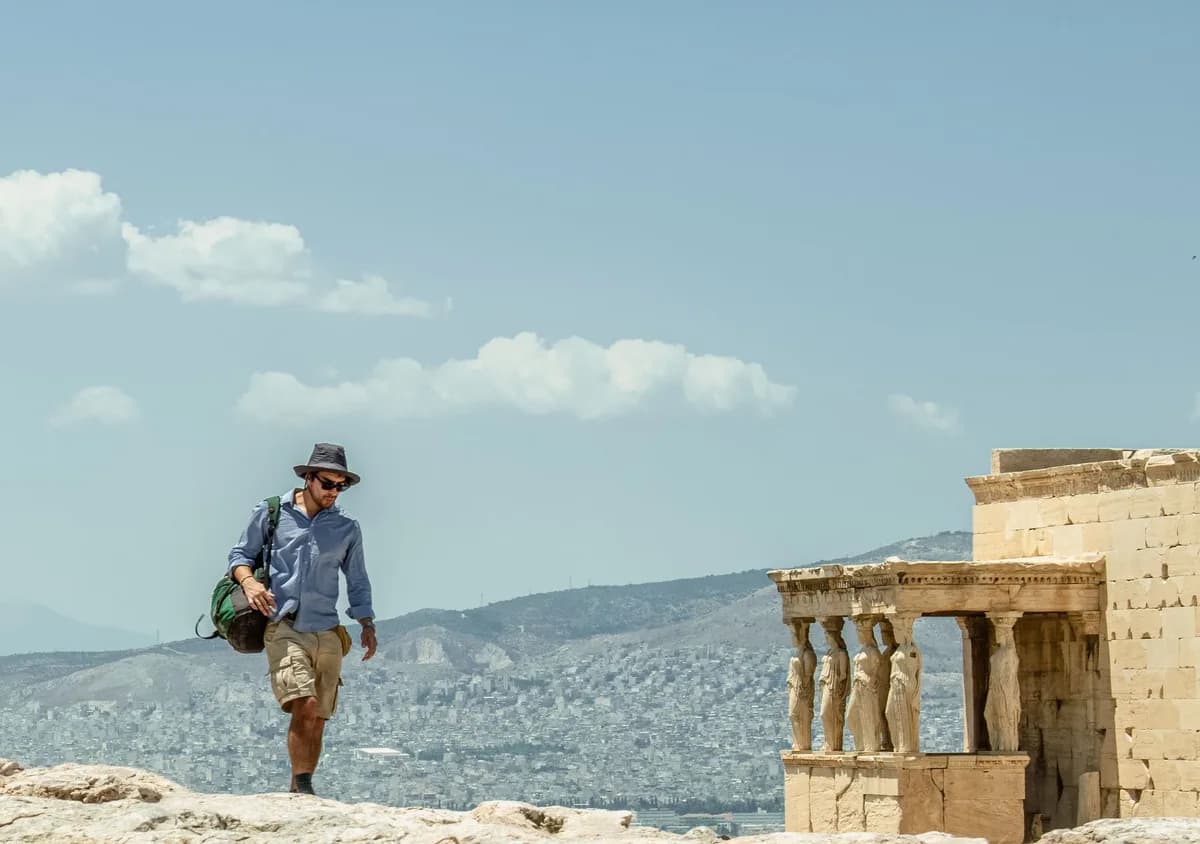 A man walking near the Erechtheion temple, enjoying a sunny day in Athens, Greece.