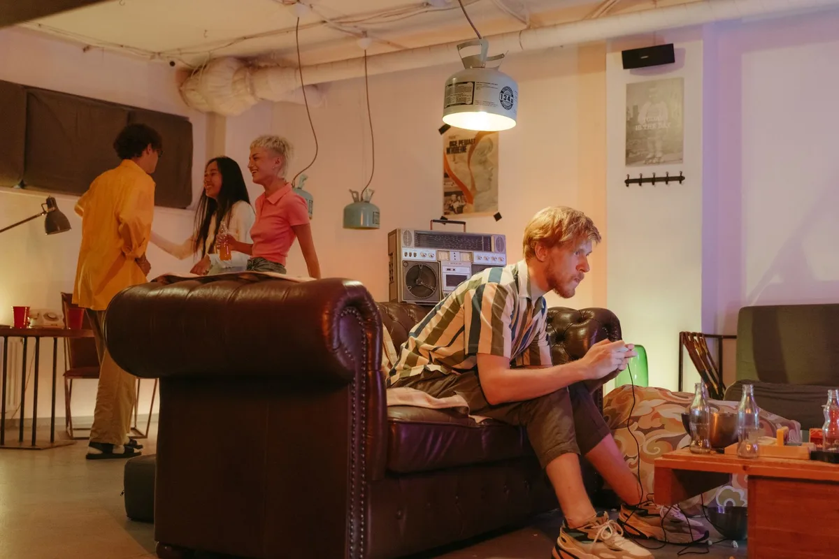 A lively scene of young friends enjoying an indoor gathering with games and music.