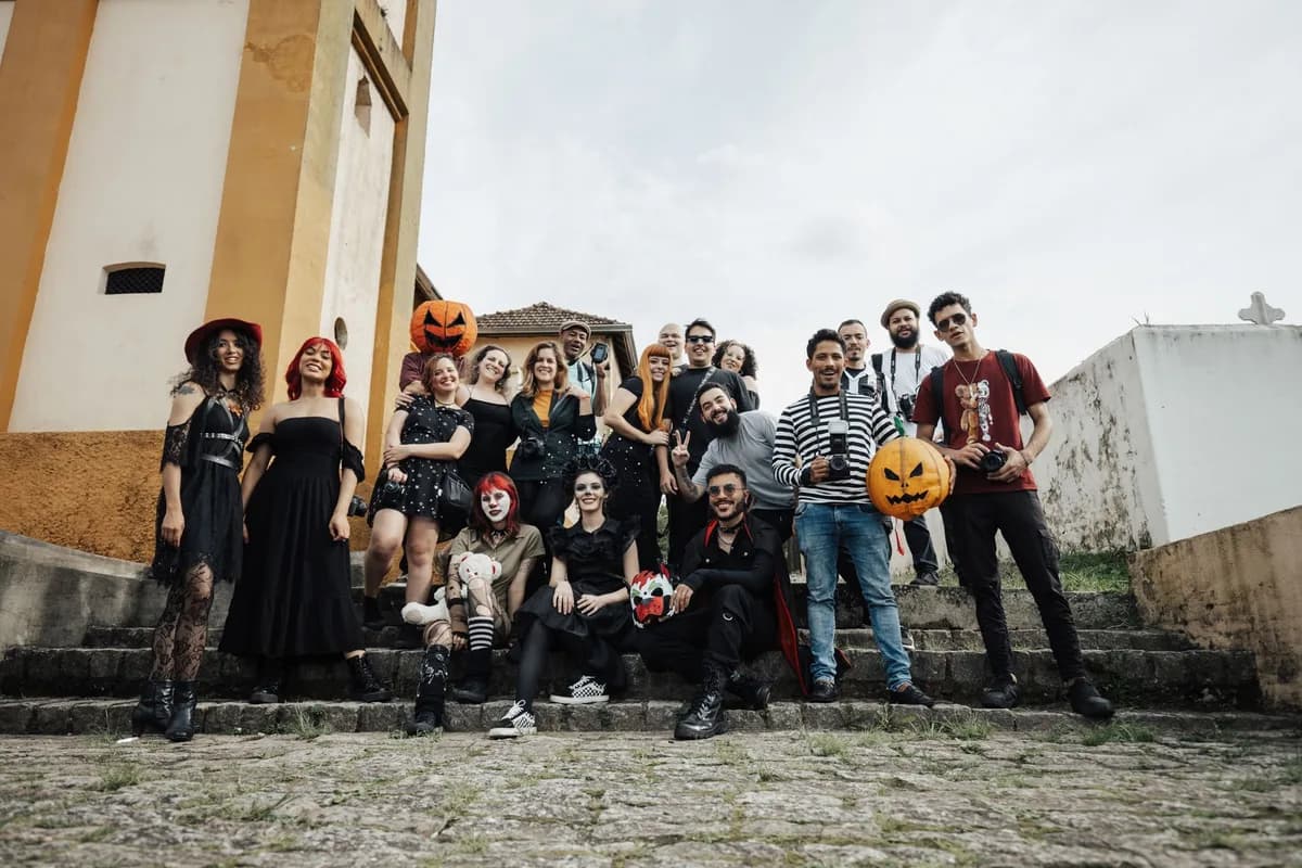 A cheerful group in Halloween costumes with pumpkins on outdoor stone steps.