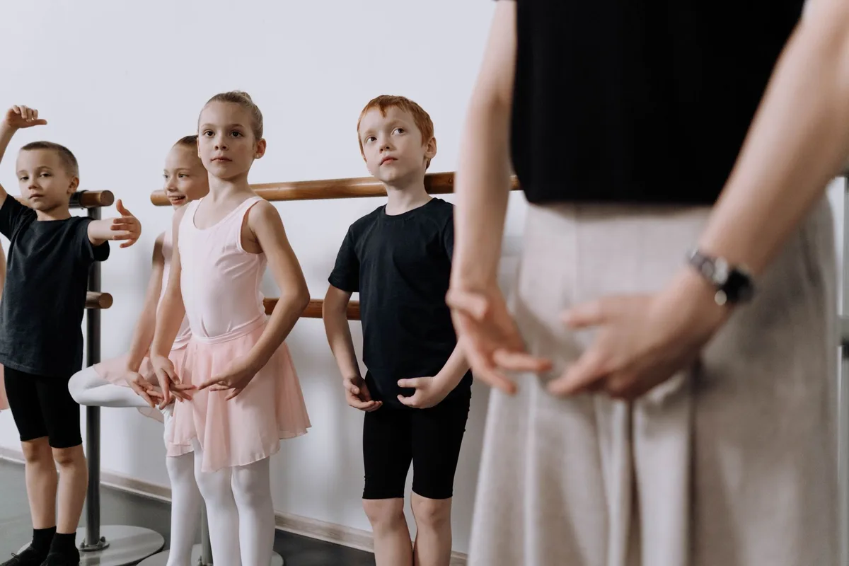 A group of children in a ballet class with their instructor, focused on their practice.