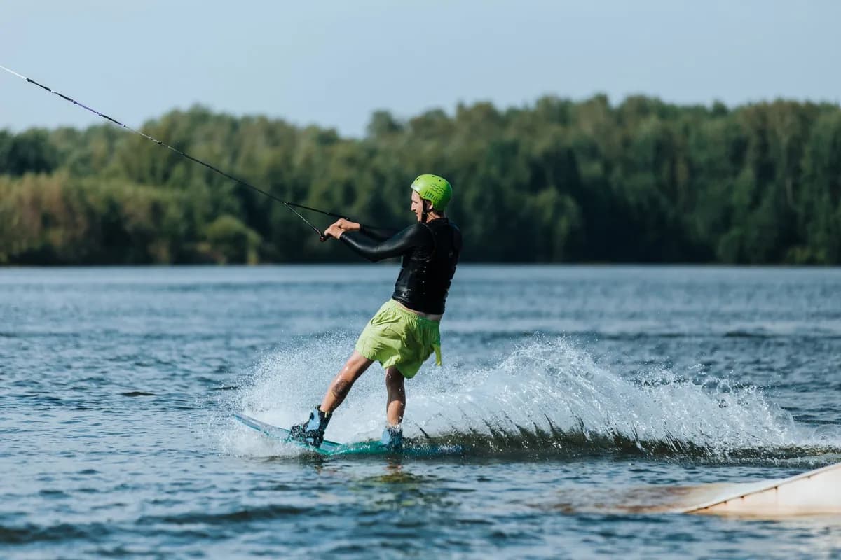 An adult male enjoying a thrilling wakeboarding session on a serene lake.