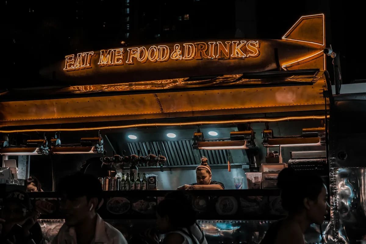 Neon-lit food truck serving vibrant street food in a bustling urban night scene.