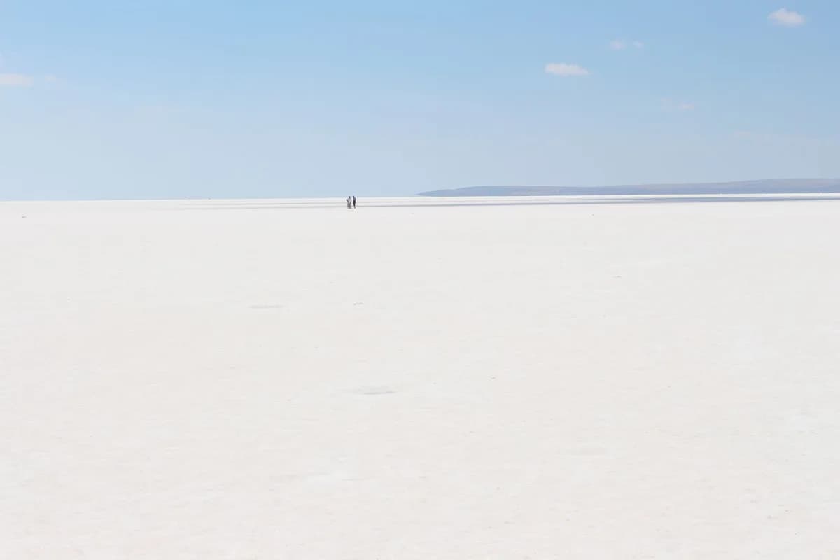 Expansive white salt flats in Şereflikoçhisar, Türkiye under a clear blue sky.